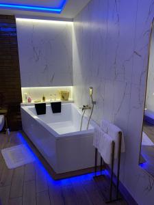 La salle de bains est pourvue d'une baignoire blanche et de lumières bleues. dans l'établissement Apartament "Love" Centrum z dużą wanną dla Dwojga, à Gniezno