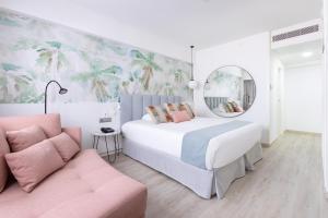 a bedroom with a large bed and a pink couch at Hotel Cristina by Tigotan Las Palmas - Adults Only in Las Palmas de Gran Canaria