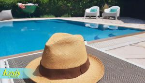 un sombrero de paja sentado en una mesa junto a una piscina en Ionis Studios, en Lefkada