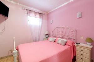 ein rosafarbenes Schlafzimmer mit einem rosa Bett und einem TV in der Unterkunft La Maximoise in Sainte-Maxime