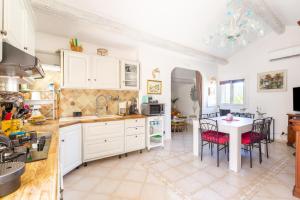 eine Küche mit weißen Schränken sowie einem Tisch und Stühlen in der Unterkunft La Maximoise in Sainte-Maxime
