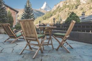 2 Stühle und ein Tisch auf einer Terrasse mit einem Berg in der Unterkunft Antares Hotel in Zermatt