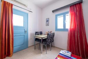 Habitación con mesa, sillas y puerta azul en Adelphi Apartments, en Perissa
