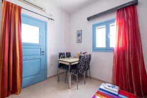 een kamer met een tafel en stoelen en een blauwe deur bij Adelphi Apartments in Perissa