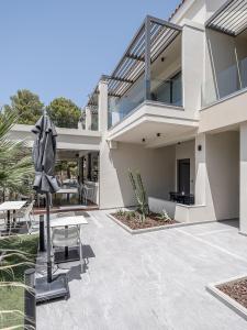 a patio of a house with a table and chairs at Mossa Well Being Hotel in Kato Daratso