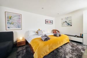 a bedroom with a bed with a yellow blanket at The Barn and Chaffhouse-Beautifully renovated Welsh Barn in Pembrokeshire in Castlemartin