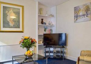 a living room with a television and a table at Cosy Cottage In Cardigan in Cardigan