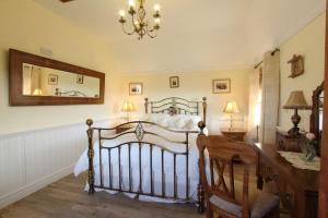 a bedroom with a bed and a mirror and a chair at Smiddy Cottage in Pollachar