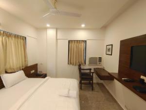 - une chambre avec un lit, un bureau et une télévision dans l'établissement Astha Residency, à Mumbai