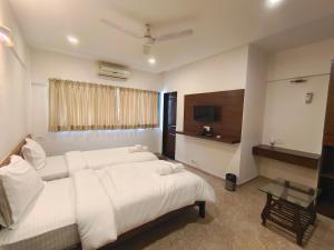 Cette chambre comprend deux lits et une télévision. dans l'établissement Astha Residency, à Mumbai
