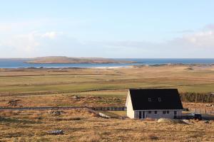 a house in a field with the ocean in the background at Clachan Sands Cottage in Balmartin