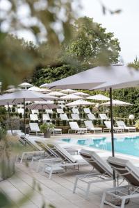 un gruppo di sedie e ombrelloni a bordo piscina di Red's Redaelli Hotel a Barzanò