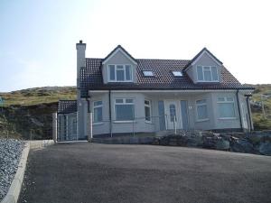 a white house with a fence in front of it at Eriskay Views Cottage in Eriskay