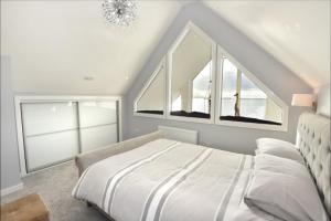a white bedroom with a bed and two windows at Rionnag Lodge in Gairloch