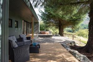 a porch of a house with chairs and a tree at Am Bothan in Lochearnhead