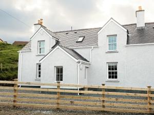 una casa blanca con una valla de madera delante de ella en Taigh Eachainn, en Valtos