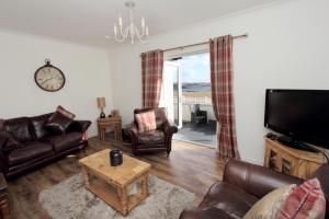 a living room with leather furniture and a tv at Dunraven in Stornoway