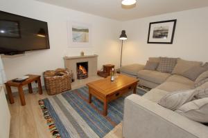ein Wohnzimmer mit einem Sofa und einem Kamin in der Unterkunft Katie's Cottage in Amhuinnsuidhe