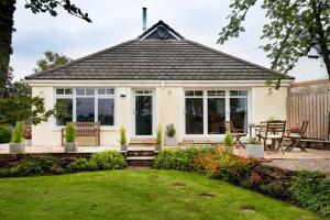 a white house with a patio and a yard at Gaidrew Cottage in Drymen