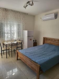Schlafzimmer mit einem Bett, einem Tisch und einem Kühlschrank in der Unterkunft Guest house Ashdod-beach in Aschdod