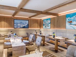 um restaurante com mesas e cadeiras e montanhas na parede em Hotel & Spa Sonne 4 Sterne Superior em Kirchberg in Tirol