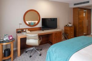 a bedroom with a desk with a television and a bed at Crowne Plaza London - Docklands, an IHG Hotel in London