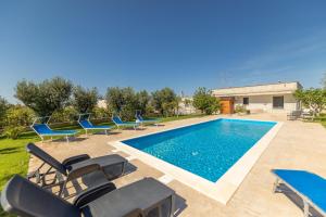 una piscina con sillas y una piscina en Villa Campagnola, en Carpignano Salentino