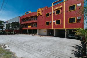 ein rotes Gebäude mit einem Parkplatz davor in der Unterkunft RedDoorz @ Golden Skye Hotel Guagua in Guagua