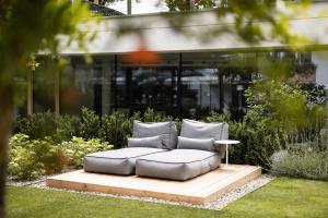 a couch sitting on a wooden platform in a garden at Boutique Hotel Zum Rosenbaum in Nalles