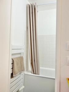 uma casa de banho branca com uma banheira e uma cortina de chuveiro em Appartement élégant avec vue sur le port em Saint-Martin-de-Ré