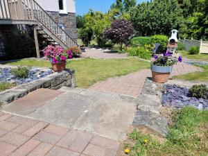 a garden with two potted flowers on a brick path at Llys Bach Apartment at Llys Aeron in Aberaeron