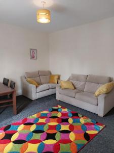 uma sala de estar com dois sofás e um tapete colorido em The Cosy 2 bedroom flat, sleeps 6 em Hebburn-on-Tyne