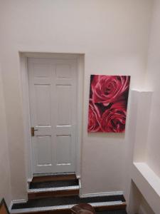 a white door with a painting of roses on the wall at The Cosy 2 bedroom flat, sleeps 6 in Hebburn-on-Tyne