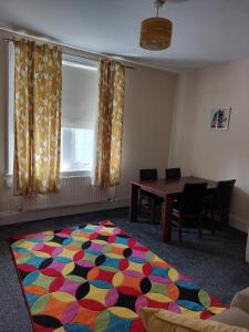 um quarto com uma mesa e um tapete colorido no chão em The Cosy 2 bedroom flat, sleeps 6 em Hebburn-on-Tyne