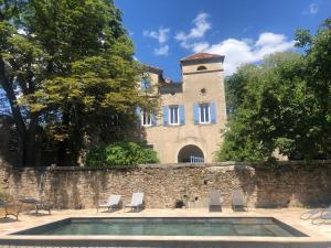 a building with a swimming pool in front of a wall at Les Dames de Saint Florent in Saint-Florent-sur-Auzonnet