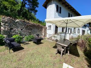 eine Terrasse mit einem Tisch, Stühlen und einem Sonnenschirm in der Unterkunft Casale a la campagne in San Mauro Torinese
