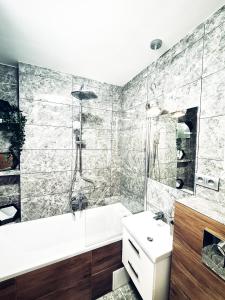 a bathroom with a shower and a tub and a sink at Apartament nad Pisą in Pisz