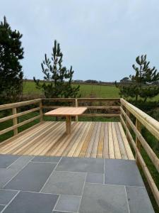 a wooden bench sitting on top of a wooden deck at Rural Wood Cabin - less than 3 miles from St Ives in Penzance