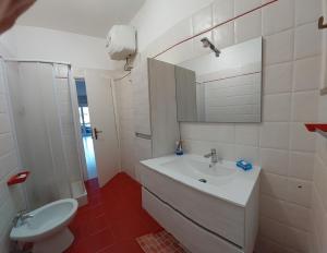 een badkamer met een wastafel, een toilet en een spiegel bij Maralis Portorosa in Furnari