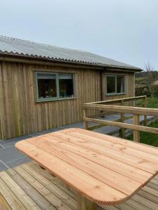a wooden picnic table on a deck in front of a house at Rural Wood Cabin - less than 3 miles from St Ives in Penzance