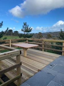 a wooden deck with a picnic table and a fence at Rural Wood Cabin - less than 3 miles from St Ives in Penzance