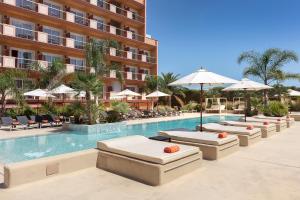 uma piscina do hotel com espreguiçadeiras e guarda-sóis em Luna Park Hotel Yoga & Spa em Malgrat de Mar