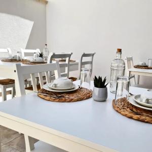 a white dining table with white chairs and plates on it at 180Passi B&B in Lido Marini