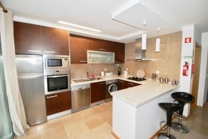 uma cozinha com armários de madeira e electrodomésticos de aço inoxidável em Whale - Apartment with Wi-Fi and heated pool em São Martinho do Porto