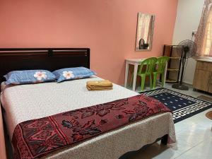 a bedroom with a bed and a green chair at Bilik Harian Pengkalan Chepa in Pengkalan Cepa