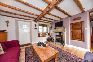 a living room with a red couch and a fireplace at Old Horns Cottage, Higham Derbyshire in Alfreton
