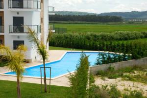 una piscina en un patio junto a un edificio en Pebble - 1 bedroom apartment sleeps 5 with pool & tennis court, en São Martinho do Porto