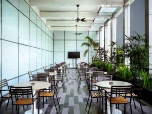 a row of tables and chairs in a room with plants at Grand Mercure Jakarta Harmoni in Jakarta