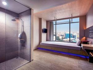 a bathroom with a bed and a shower and a window at Grand Mercure Jakarta Harmoni in Jakarta