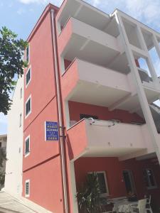 ein rot-weißes Gebäude mit einem blauen Schild darauf in der Unterkunft City Apartment Damir in Makarska